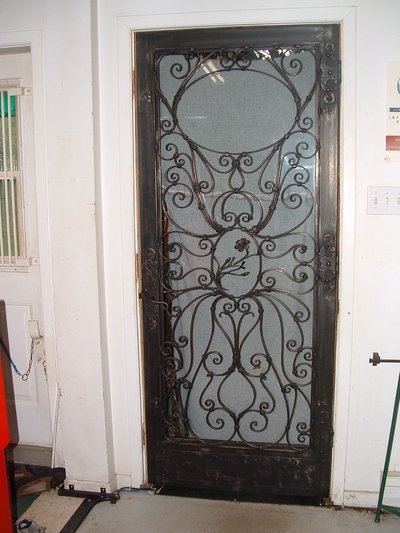 Grille de porte en fer forgé avec volutes et motifs floraux